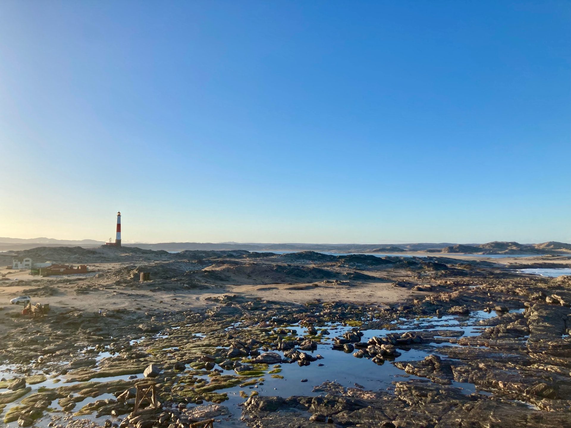 A red and white lighthouse above the rocky tidal shoreline near Lüderitz on the Atlantic coast